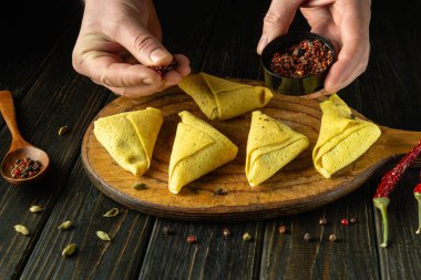 Nalisniki 'ye baharat ya da katlanmış krep ekliyorum. Aşçı yemek hazırlarken ya da Ukrayna ulusal yemeği hazırlarken ellerini yakınlaştırıyor.