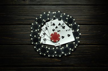 Koyu renkli bir masada bir sürü siyah fiş ve iskambil kağıdı. Poker kulübünde ya da kumarhanede şans ya da kayıp kavramı.