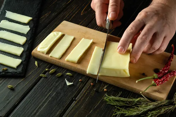 Aşçı elleri bıçakla Mozzarella peynirini bir restoran mutfağında aperatifleri hazırlamak için kesiyor. Kahvaltı için nefis atıştırmalıklar..