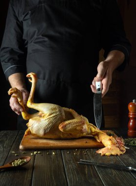 Mutfak masasında çiğ horoz pişirmek. Izgarayı pişirmeden önce mutfak masasında tavuk kestiği için bir şefin elinde bıçak..