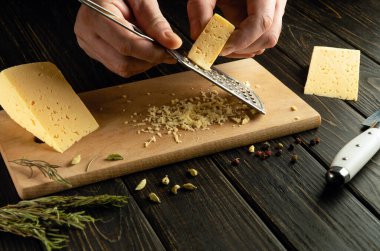 Mutfak tahtasında sert Hollanda peyniri rendelemek. Peynir yemeği hazırlamak için gösterişsiz bir konsept. Tarif yeri.