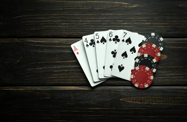 A combination of high card playing cards and winning chips on a black vintage table. Low key concept of a big winning combination in a poker club or casino.