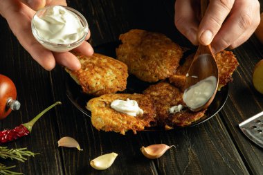 Aşçı patatesli gözlemelere bir kaşıkla ekşi krema ekler. Öğle yemeğinde lezzetli sebze servisi yapmak gibi basit bir kavram..