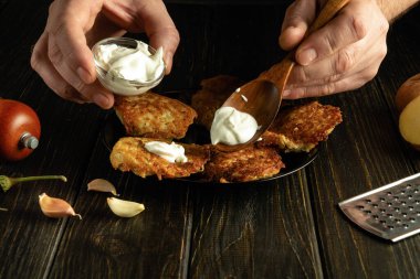 Garsonun elleri kızarmış patatesli gözlemelere bir kaşıkla ekşi krema ekler. Lokantada öğle yemeğinde lezzetli yemekler servis etmek gibi basit bir kavram..
