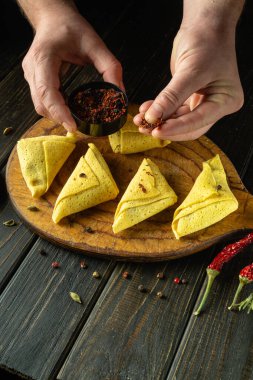 Aşçı elleri pişirmeden önce ince yuvarlanmış kreplere baharat ekler. Mutfak masasında nefis bir kahvaltı hazırlama konsepti..