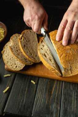 Akşam yemeğinden önce ekmek dilimlemek ve mutfak tahtasının üzerinde yemek pişirmek. Gösterişsiz fırın, doyurucu gıda konsepti. Reklam alanı.