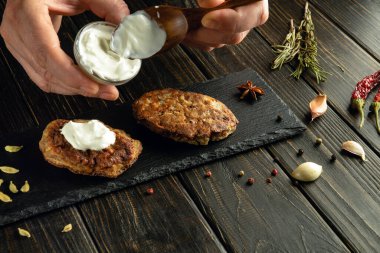 Kreplere ekşi krema ekliyorum. Ellerinde de kaşık var. Bardaki bir mutfak masasında çalışma ortamı.