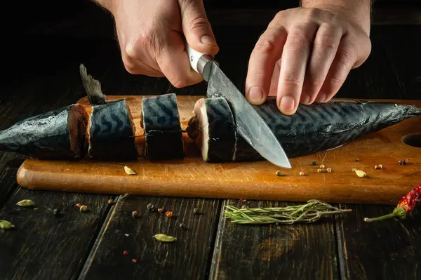 stock image Chef preparing fresh mackerel on the kitchen table. Low key concept for preparing a fish dish. Slicing Scomber fish with a knife.