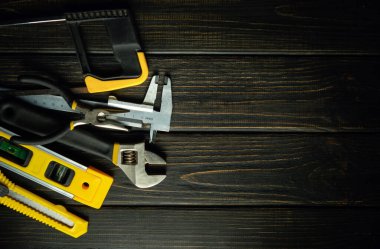 Siyah bir şarap masasının üzerinde tamir ve inşaat için profesyonel bir alet seti bulunur. Yenileme çalışmaları için basit bir hazırlık konsepti.