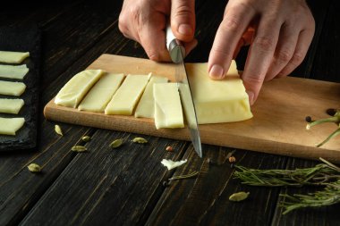 Mozzarella peynirini servis için dilimlemek için bıçak kullanan bir adamın yakın çekimi. Lokantada lezzetli bir mandıra servisi yapma fikri..