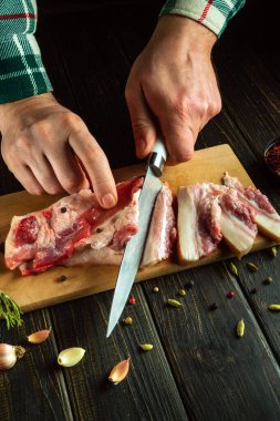 Bir şef, akşam yemeğine hazırlanmadan önce domuz eti ya da domuz eti kesmek için bıçak kullanır. Konsept, sağlıklı ve yağlı yiyecekler hazırlamak için sade bir anahtar..