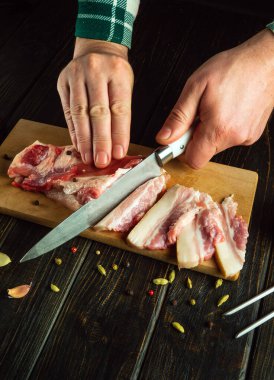 Lezzetli bir sarımsaklı atıştırmalık hazırlamadan önce mutfak tahtasındaki bıçakla domuz eti dilimleyen bir aşçı. Basit bir köy yemeği ya da atıştırmalık konsepti..