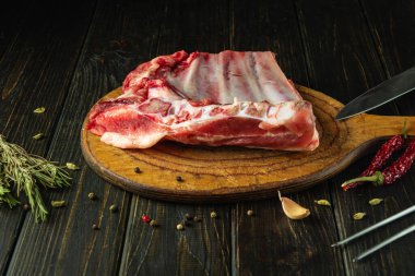 Kesme tahtasındaki çiğ pirzola dilimleme ve pişirmeden önce bıçakla yenir. Mutfak masasında baharat ve etle birlikte çalışma ortamı. Avrupa mutfağı.