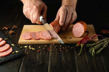 Et sosisi dilimliyorum. Sokak restoranında abur cubur için sosis hazırlama ya da servis etme kavramı. Bir aşçının elinde bıçak..