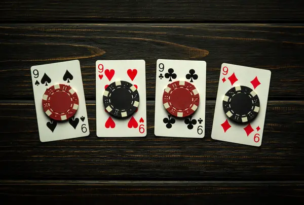 A gambling game of poker with a lucky winning combination of four of a kind or quads. Playing cards and chips on a black vintage casino table.