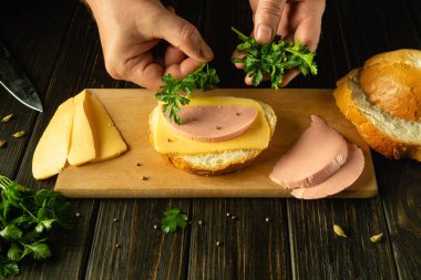 Mutfak masasındaki restoranda sandviç hazırlıyorum. Şefin eli sandviçe taze maydanoz ekler. Reklam alanı.