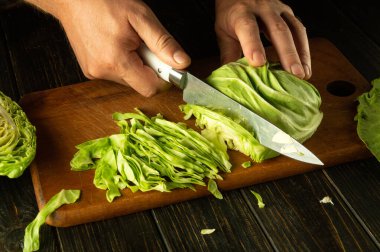 Şef elleri vejetaryen yemeği hazırlamak için taze lahana kesti. Bardaki mutfak masasında ulusal lahana yemeği pişiriyorum..