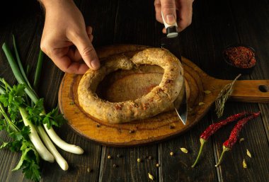 Lokantada leziz bir öğle yemeği için mutfak tahtasına kesilmiş domuz sosisi dilimlenmiş bir bıçakla şefin elleri. Bayram sofrasında servis edilen ulusal yemek..