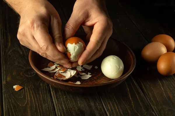 Hands peel an egg. Chef hands peeling boiled eggs on the kitchen table before preparing breakfast.