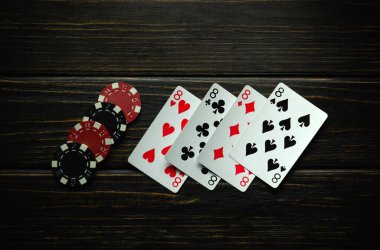 Çipler ve iskambil kağıtları. Koyu renkli bir masada dört çeşit ya da dördüncünün kazanan kombinasyonu. Poker kulübünde ya da kumarhanede kazanma kavramı.