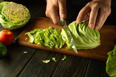 Aşçı sebzeli salata hazırlamak için taze lahanayı bıçakla keser. Vejetaryen yemeği hazırlamak için basit bir kavram..