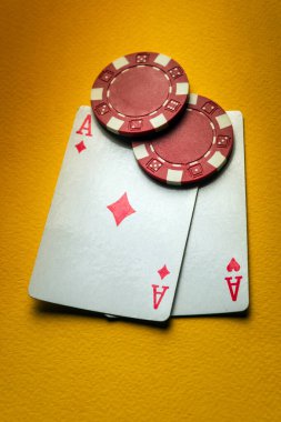 Poker fişleri ve kâğıtlar, sarı bir masada bir çift kazanan kombinasyonla. Şans şansa bağlıdır..