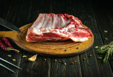 Dilimleme ve pişirmeden önce kesme tahtasının üzerinde çiğ kuzu kaburgası. Baharat ve etle dolu eski mutfak masasında çalışma ortamı. Asya mutfağı.