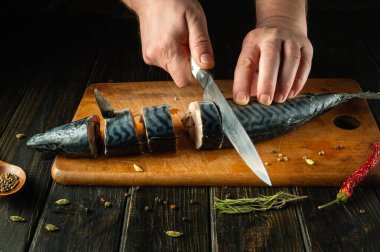 Şef akşam yemeği için bir tabak hazırlamak için uskumru balığını parçalara ayırır. Basit bir balık diyeti konsepti. Reklam alanı.