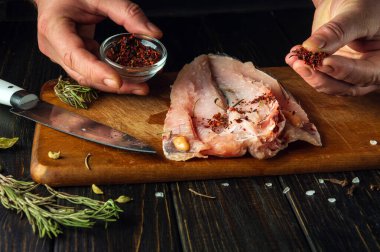 Şef taze Hake balık filetosuna kuru aromatik baharatlar ekler. Eşsiz bir tarifle ulusal bir balık yemeği hazırlama kavramı.