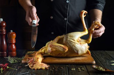 Bir aşçı mutfak masasında çiğ bir horoz hazırlar. Akşam yemeği için tavuk ya da horozdan zengin bir çorba hazırlama kavramı.