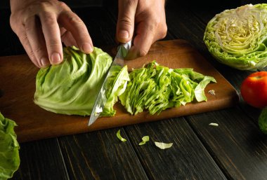 Şefin elleri taze lahana kesmek için büyük bir tava ve bıçakla. Lahana ve sebzeli vejetaryen yemeği pişirme kavramı.