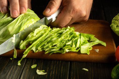 Lahana salatası yapıyorum. Bıçak şefin elinde, mutfak tahtasındaki taze lahana kesiyor..