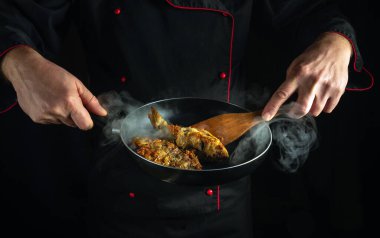 Kahvaltı için kızartma tavasında balık kızartma şefi. Balık yemeğinin siyah arkaplan kavramı.