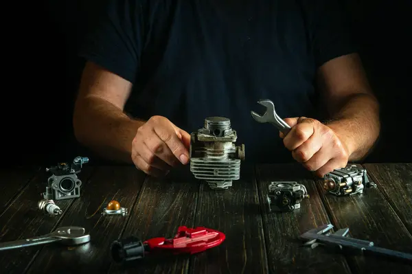 stock image Repair of a petrol trimmer engine cylinder on a workshop table by a repairman.