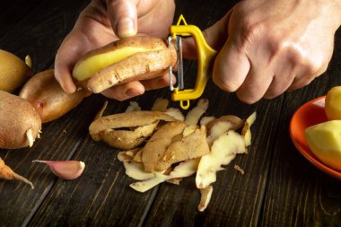 Yemek ya da sebze yemeği hazırlamak için patates soyan bir aşçı..