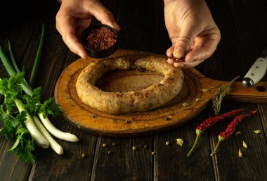 Erkek eli, ev yapımı sosise aromatik baharatlar ekler. Sosisi evde tatil masasına hazırlama konsepti.