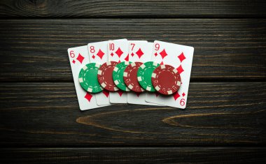 Siyah antika masanın üzerinde floş ve floş kombinasyonları olan çipler ve iskambil kağıtları. Poker kulübünde veya kumarhanede kazanma kavramı.