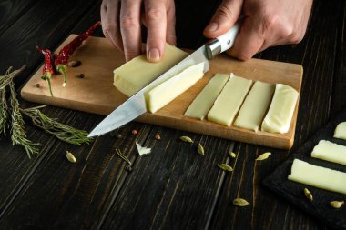 Bir adamın elinde bıçakla süt peyniri doğramak.