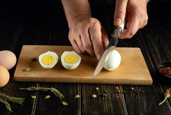 stock image A chef preparing an egg dish by hand on a kitchen table.