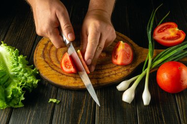 Taze sebzelerden salata hazırlıyorum. Vejetaryen yemeği için bir şefin elinde bıçakla domates kesmek..