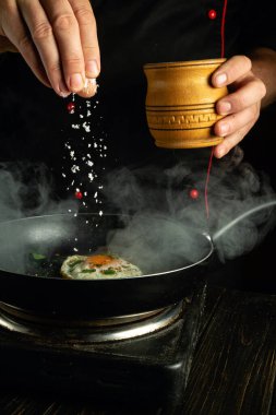Profesyonel bir aşçı yumurta hazırlar ve tavaya tuz ekler..