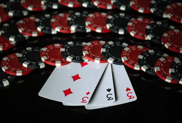 Three aces on the background of chips received from winning or successful combination of three kind or set. Concept of successful victory in poker club on black background.