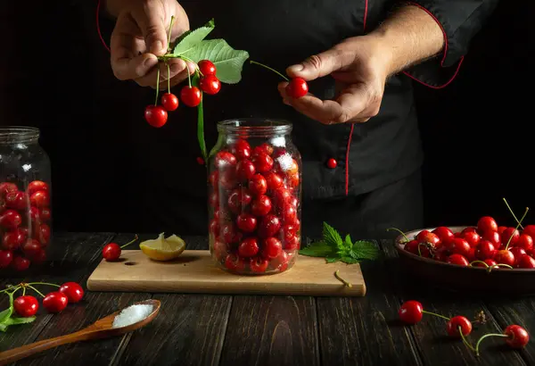 stock image Preparing canned sweet cherry. A person places cherries into a jar with his hands before rolling.