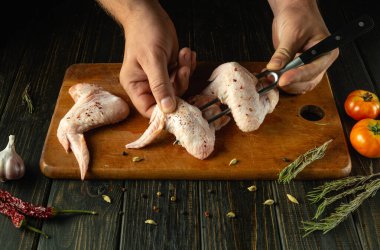 Şef çatala tavuk kanadı takıyor. Restoranda ya da otelde iş hizmeti kavramı. Mutfak masasında bufalo kanatları pişiriyorum..