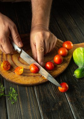 Şef mutfak masasında sebze kahvaltısı hazırlıyor. Pişirmeden önce vişneli domates doğramak. Domates diyet menüsü.