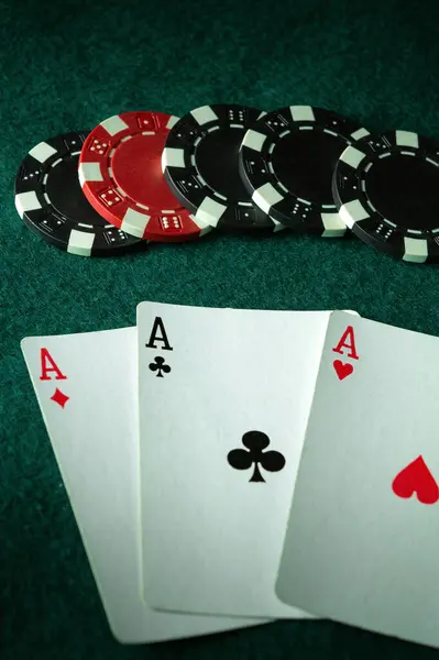 stock image A lucky combination of playing cards three of a kind or set. Chips and cards on a green table in a poker club. A big win depends on fortune.