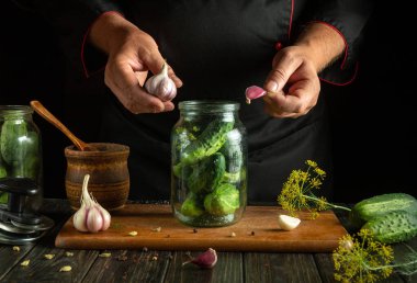 Aşçıların elinde kavanozda sarımsaklı salatalık turşusu. Atıştırmalık salatalık konsepti.