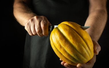 Şef lokantada tatlı olarak kavun kesmek için bıçak kullanıyor. Olgun kavun servis etmenin gösterişsiz bir konsepti. Siyah arkaplanda reklam alanı.