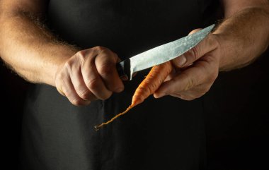 Bir şefin elinde bıçakla havuç soyuyordu. Havuç yemeği pişirme konsepti. Kısıtlı aşçı diyeti fikri.
