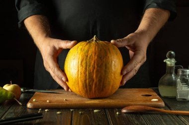 Aşçı pişirmeden önce mutfak tezgahında büyük bir balkabağı. Sebze diyeti ya da ulusal yemek pişirme kavramı..